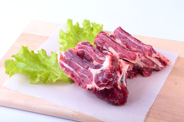 Raw beef edges and lettuce leaf on wooden desk isolated on white background from above and copy space. ready for cooking