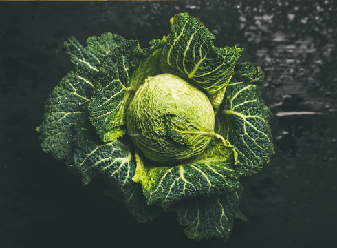 Raw fresh green cabbage over dark background, top view, selective focus, horizontal composition