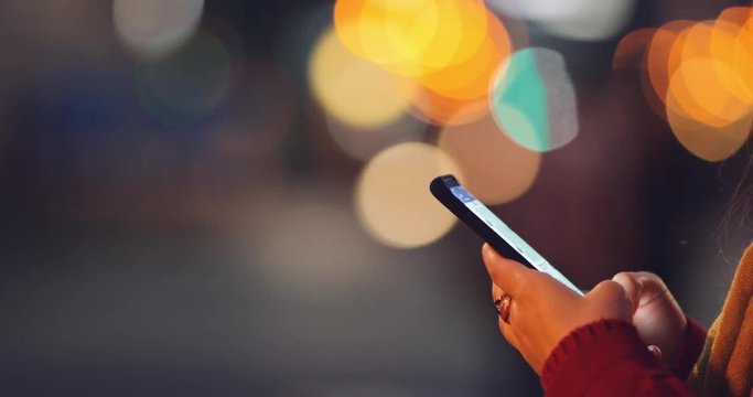 Woman Hands Using Smartphone at Dusk in the City, Close Up. 4K SLOW MOTION. Millennial Girl reading on cell phone, using app social media, texting. Blurred Night Street lights background.