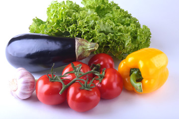 Fresh assorted vegetables, eggplant, bell pepper, tomato, garlic with leaf lettuce. Isolated on white background. Selective focus.