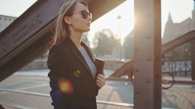 Young Businesswoman Going to Work in the Sunny Morning City. SLOW MOTION. STEADICAM Stabilized Shot. Attractive Professional Business Woman with Tablet rushing to a morning meeting. Lens Flare. 
