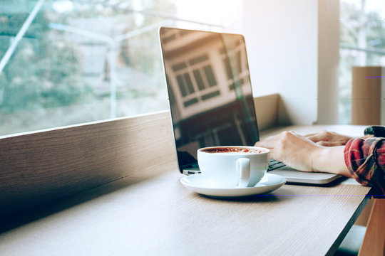 Young Asian Man Working On Laptop In Cafe And Drinking Coffee In Morning.