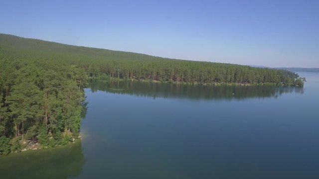 Aerial view on calm forest lake, tree forest backgrounds. Beautiful landscape. Aerial view of trees on the lake shore. Forest lake landscape with reflections
