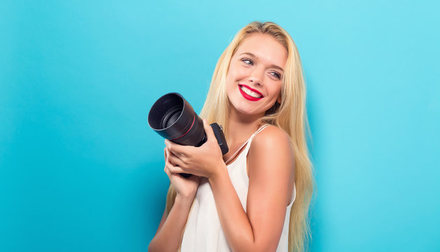Young woman comparing professional camera on a solid background