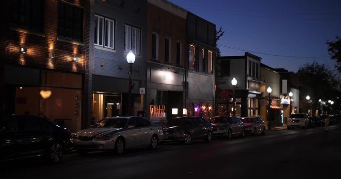 A nighttime establishing shot of businesses on a typical Main Street in America. Pittsburgh suburb.	Building names and addresses obscured.  	