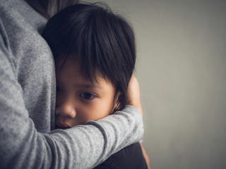Closeup sad little boy being hugged by his mother at home. Parenthood, Love and togetherness...