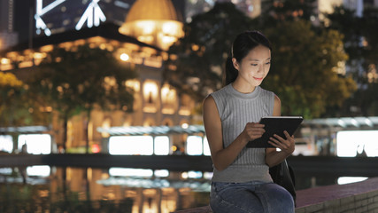 Woman use of tablet computer in city at night