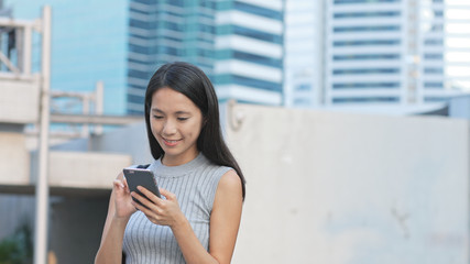 Fototapeta premium Woman sending sms on cellphone in city