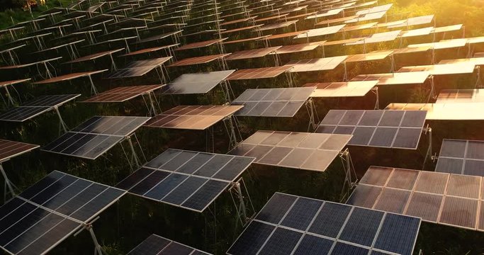 4K Aerial view of Solar Panels Farm (solar cell) with sunlight.Drone flight fly over solar panels field renewable green alternative energy concept in Thailand.