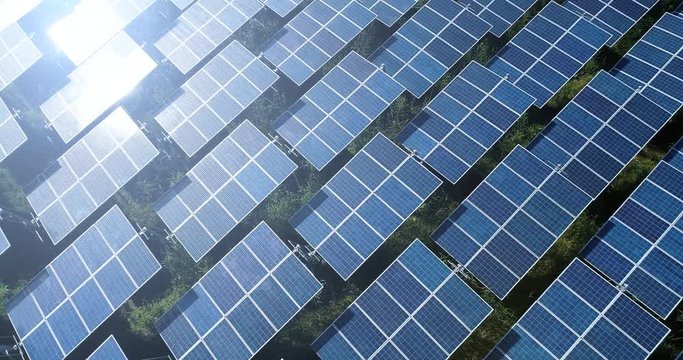 4K Aerial view of Solar Panels Farm (solar cell) with sunlight.Drone flight fly over solar panels field renewable green alternative energy concept in Thailand.