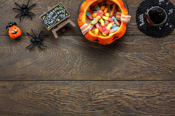 Top view of Happy Halloween decorations festival and candy trick or treat background.All accessory on modern rustic brown wooden at home office desk.Free space for creative design the text and word.