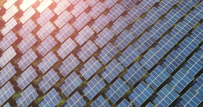 4K Aerial view of Solar Panels Farm (solar cell) with sunlight.Drone flight fly over solar panels field renewable green alternative energy concept in Thailand.