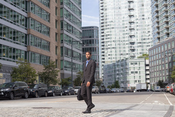 Wide shot of African American business man walking in the business district in NYC