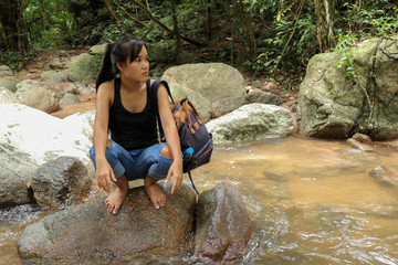 Asian women long  black hair tired and sitting on a rock at a waterfall  with nature and forest background.