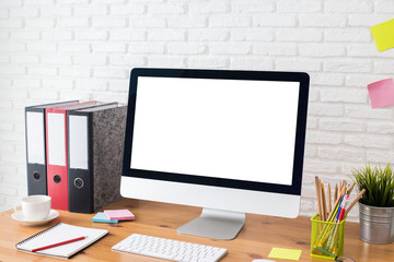 workspace with computer with blank white screen, and office supplies on a wooden desk