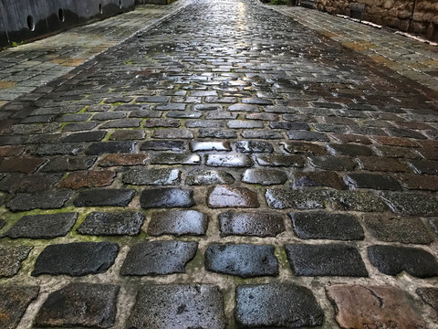 Fototapeta Small beautiful alley with wet cobblestones.