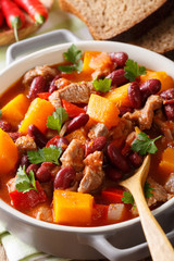 Pumpkin chili soup with beef and beans in tomato sauce macro. vertical