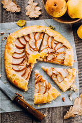 Homemade galette with pears and nuts on wooden rustic background. Sweet open fruit pie. Autumn bakery. Top view, copy space