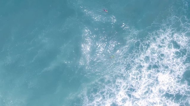 Aerial view of young man stand up paddle boarding on blue ocean waves 