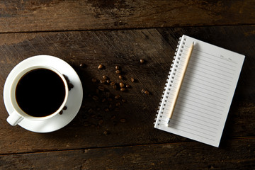 Top view of black coffee and blank notebook