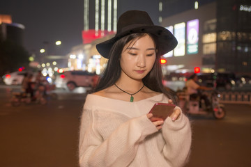 beautiful girl use a mobile phone in the streets at night