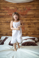 funny girl child jumping on  bed, lifestyle, rustic style,