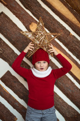 Fototapeta premium funny girl child in red hat with star, lifestyle, real interior, winter rustic style