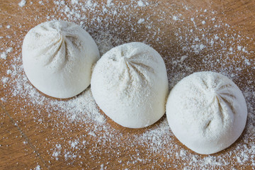 three frozen large raw khinkali on a blackboard