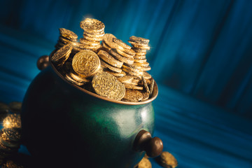 pot full of gold coins on a wooden surface and dark background / saint patricks day concept