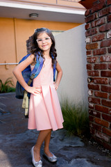 Fototapeta premium A young girl with pink glasses is excited and nervous for her first day of school.