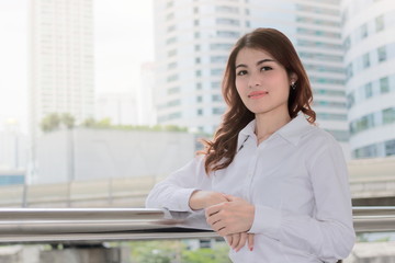 Fototapeta na wymiar Portrait of attractive young Asian businesswoman looking on camera at urban building with sunshine effect background. Leadership woman concept.