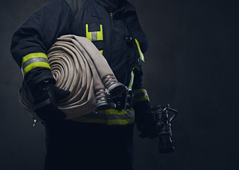 Fototapeta premium Firefighter in uniform holds fire hose.