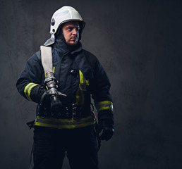 Firefighter in uniform holds fire hose.