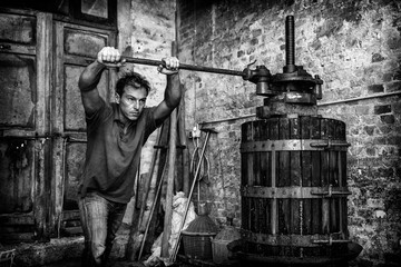 Shirtless winemaker farmer working on a traditional wine press 
