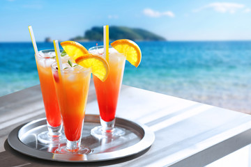 Glasses of Tequila Sunrise cocktail on metallic tray