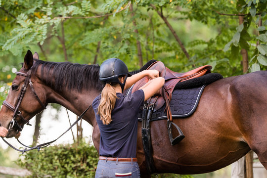 Young girl preparing horse for ride