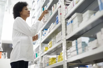 Crédence de cuisine en verre imprimé Pharmacie Femme chimiste organiser des stocks dans des étagères à la pharmacie