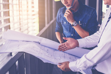 contractor and engineer with blueprints discuss at a modern construction site, Architecture and...