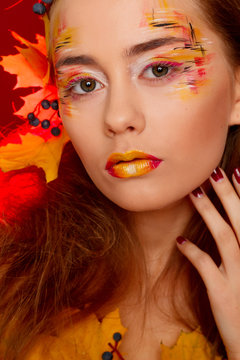 Beautiful young woman with autumn make up posing in studio over red background. Fashion concept.