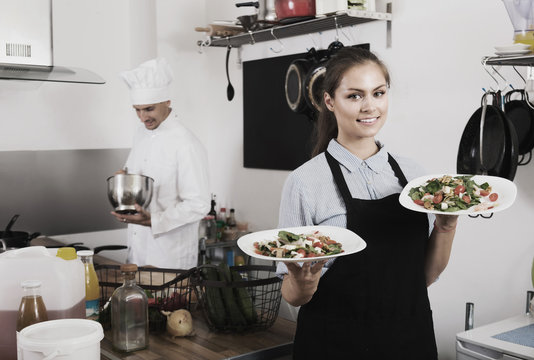 young waitress with served salad on kitchen.