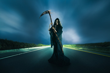 grim reaper with scythe on a road / high contrast image