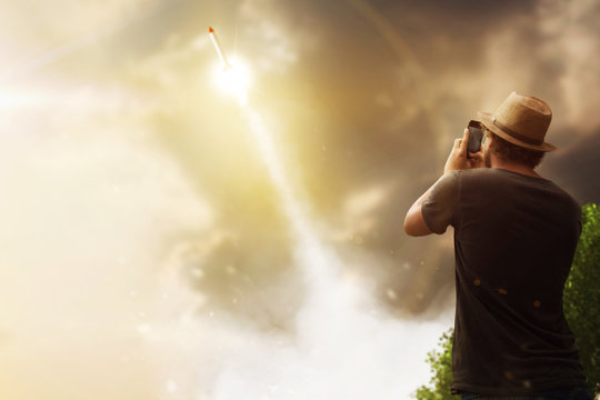 Young man recording recket launch with smartphone