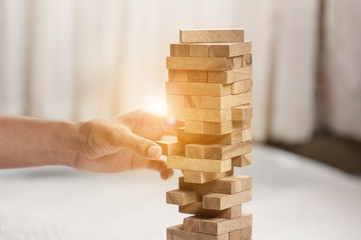hand  pulling out or placing wood block on the tower in modern office. plan and strategy in business. blur for background.