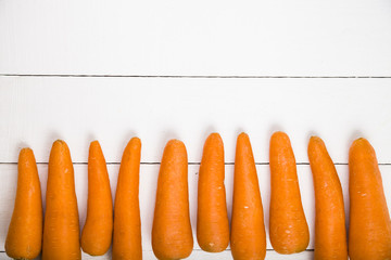 Ripe carrots on a white wooden table.