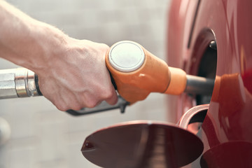 Close up. A man pumping or putting gasoline fuel in a car at gas station. Car refueling