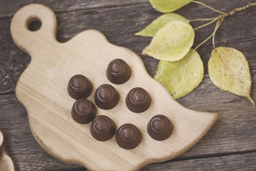 chocolate candies on a wooden Board with autumn leaves