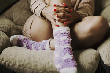 Beautiful girl in a sweater and wool socks sitting in chair