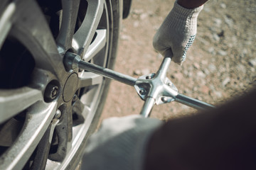 Close-up. The auto mechanic is fixing the car. Cross-key for wheels. Wheel Replacement