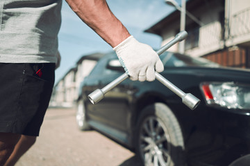 Obraz premium Close-up. The man is fixing the car. Cross-key for wheels. Wheel Replacement
