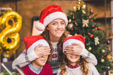 mother embracing with kids in santa hats